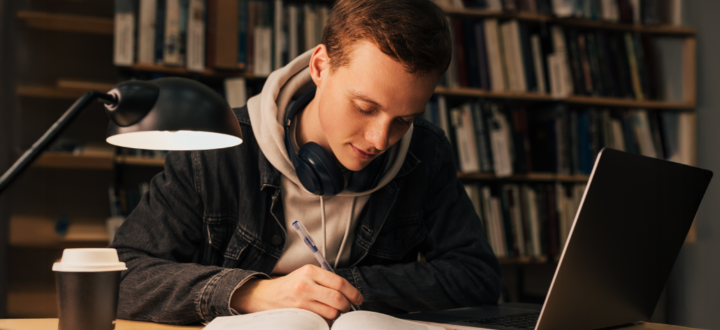 Student studying at a library desk in dim lighting