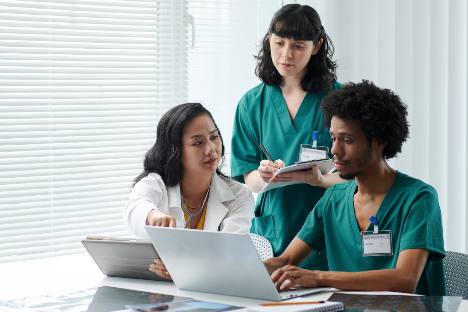 Three healthcare providers look at a laptop and tablet