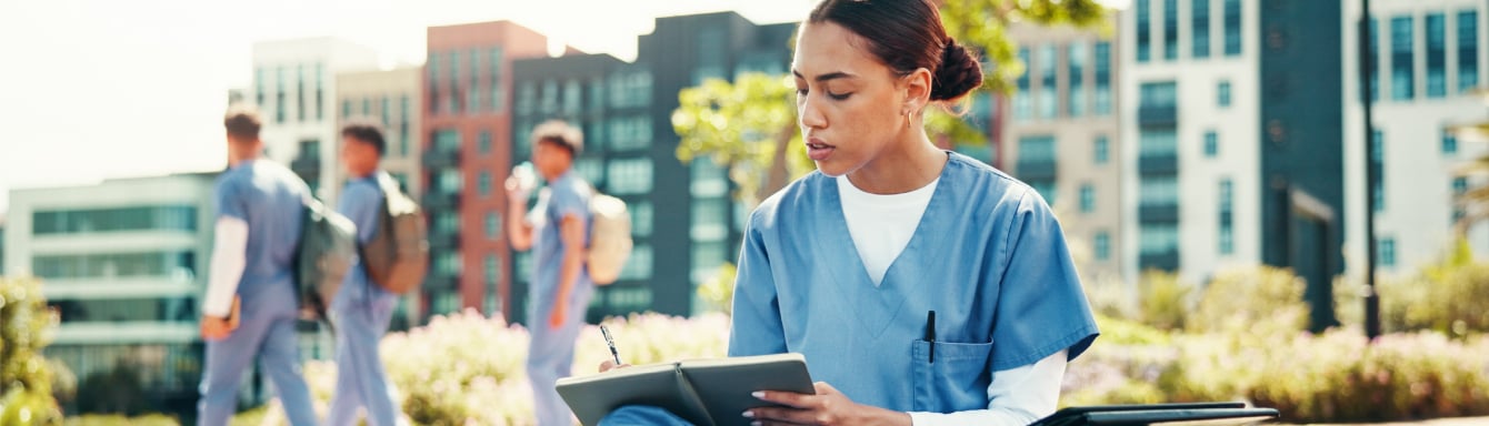 A nurse student writes notes outside